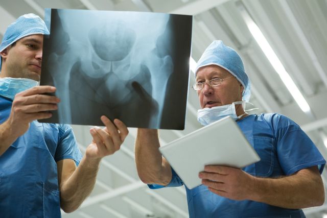 Male surgeons holding digital tablet while discussing x-ray - Download Free Stock Photos Pikwizard.com