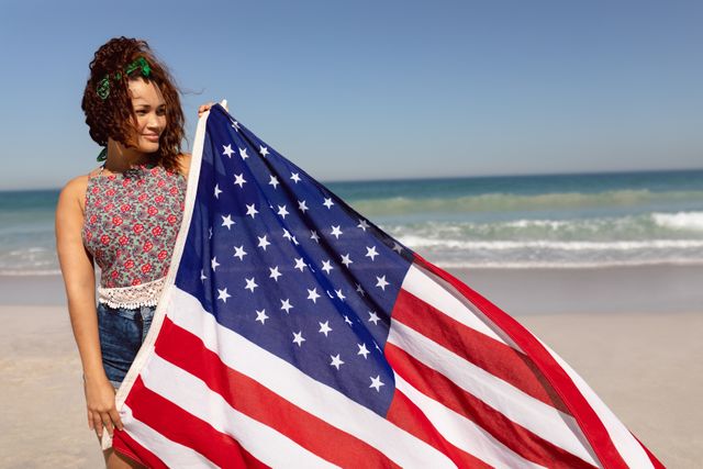 Beautiful woman holding american flag on beach in the sunshine - Download Free Stock Photos Pikwizard.com