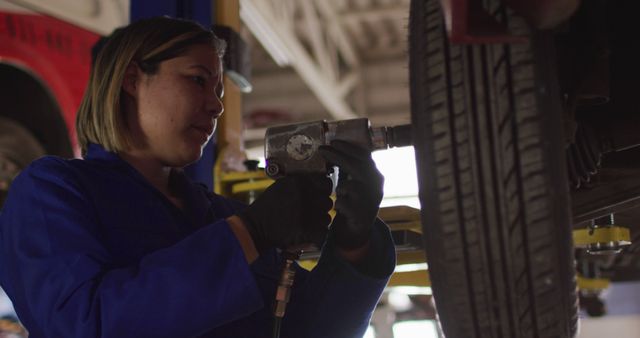 Female mechanic changing tires of the car using a power drill at a car service station - Download Free Stock Photos Pikwizard.com