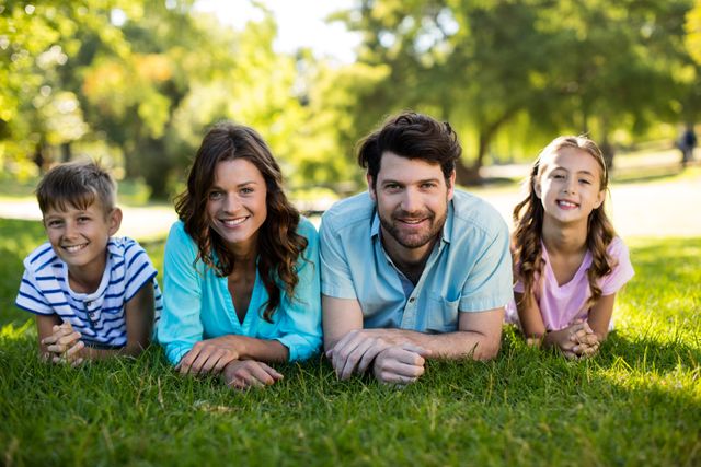 Portrait of happy family lying on grass in park on a sunny day