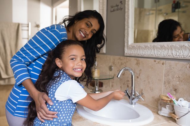 Smiling girl with mother washing hands at bathroom sink - Download Free Stock Photos Pikwizard.com