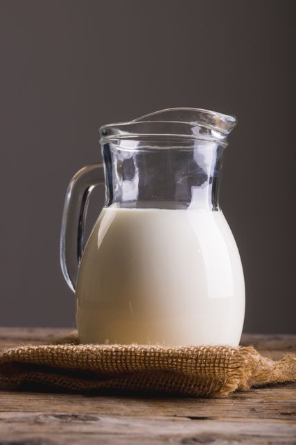 Close-up of milk in jug on table against gray background with copy space. unaltered, food, drink, studio shot and healthy eating.