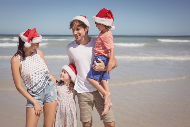 Happy family wearing Santa hat at beach - Download Free Stock Photos Pikwizard.com