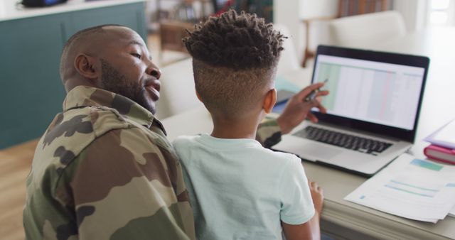African american father with son learning together with laptop. Spending quality time together, army and patriotism concept.