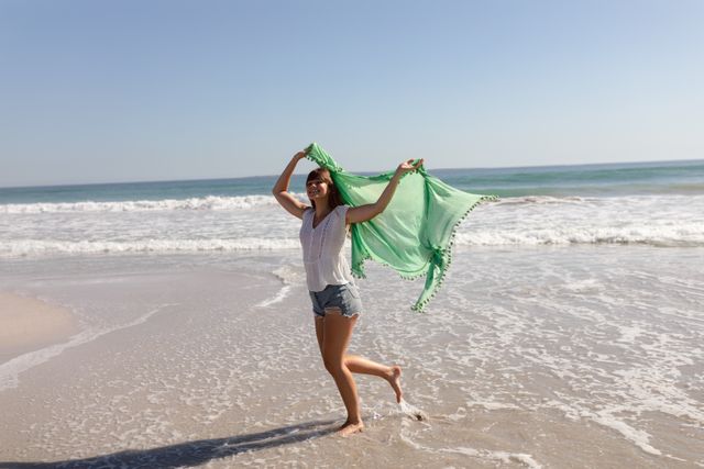 Beautiful woman waving scarf on beach in the sunshine - Download Free Stock Photos Pikwizard.com