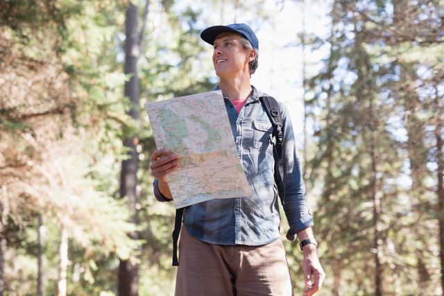 Low angle view of hiker with map standing in forest - Download Free Stock Photos Pikwizard.com