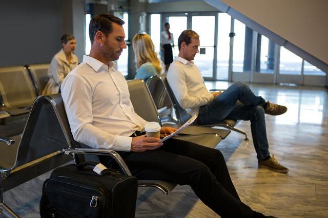 Businessman reading newspaper in waiting area at airport terminal