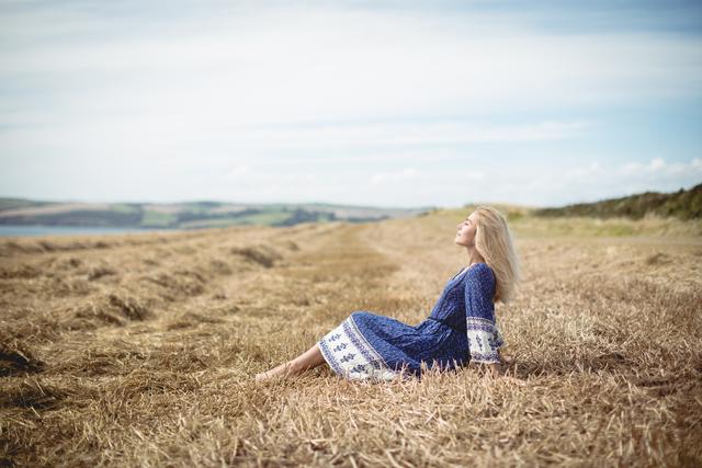 Blonde woman sitting in field - Download Free Stock Photos Pikwizard.com