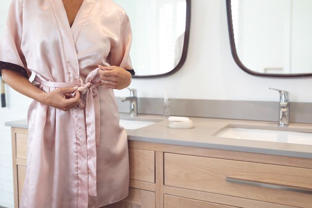 Woman tying knot of nightwear in bathroom at home - Download Free Stock Photos Pikwizard.com