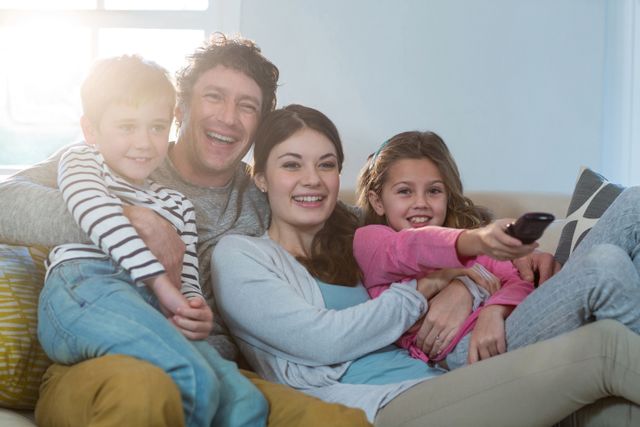 Family watching television while sitting on sofa at home
