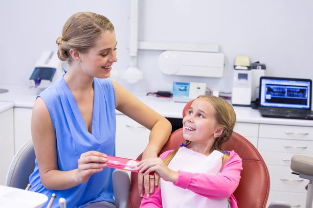 Mother giving tooth brush to daughter at dental clinic - Download Free Stock Photos Pikwizard.com
