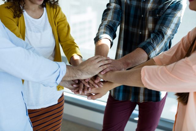 Creative business team stacking hands together in office