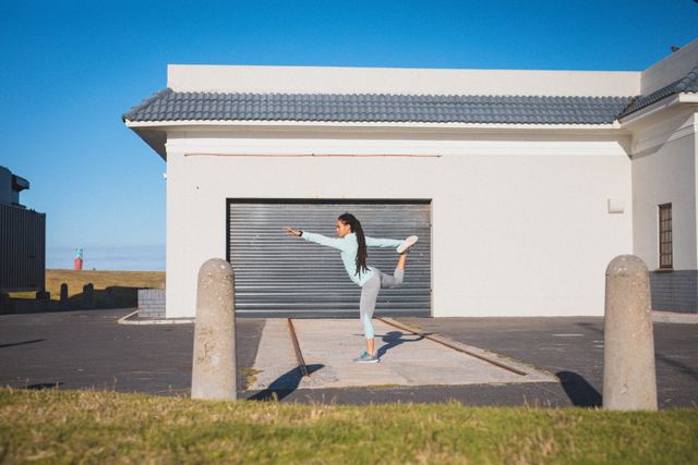 Mixed race woman with dreadlocks exercising in street stretching in front of garage door - Download Free Stock Photos Pikwizard.com