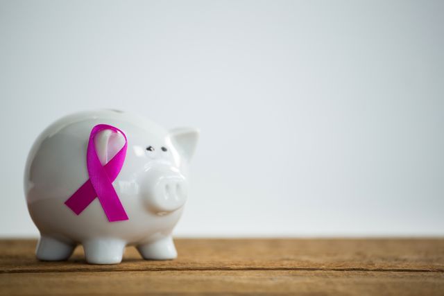 Close-up of pink Breast Cancer Awareness ribbon on piggybank over wooden table - Download Free Stock Photos Pikwizard.com