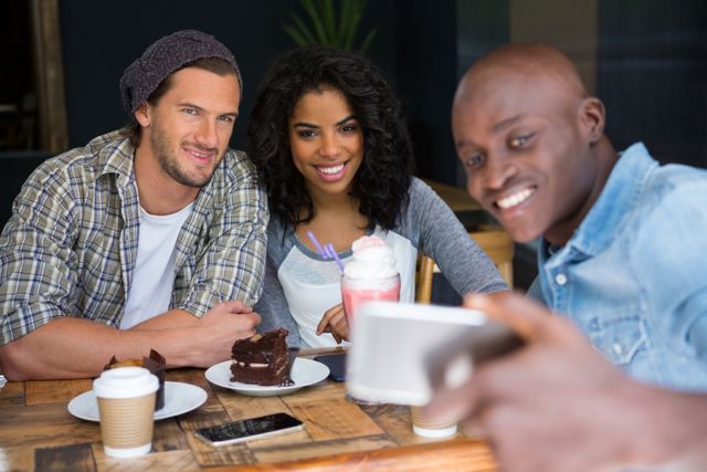Man with friends taking selfie at wooden table in coffee shop - Download Free Stock Photos Pikwizard.com