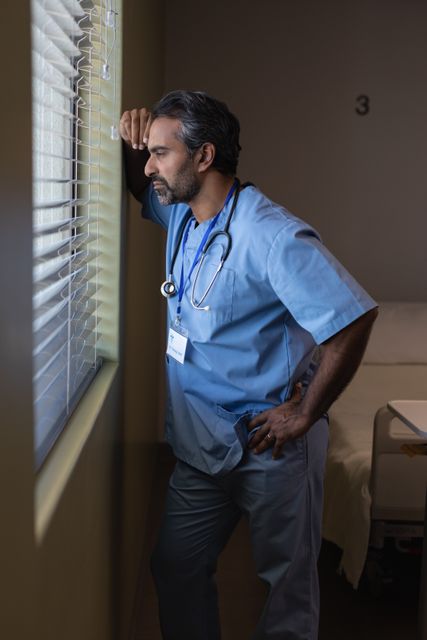 Male surgeon looking through window at hospital - Download Free Stock Photos Pikwizard.com