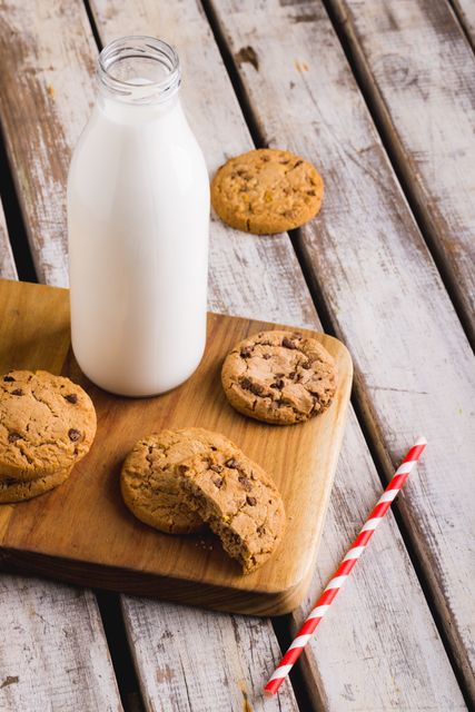 High angle view of milk bottle by cookies with straw on wooden table, copy space. unaltered, food, drink and healthy eating.