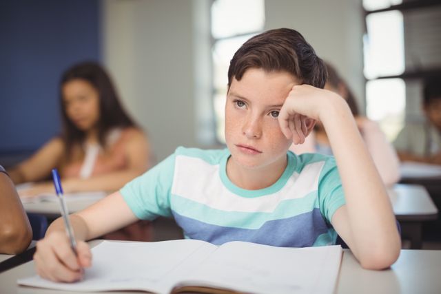 Tensed school boy doing homework in classroom - Download Free Stock Photos Pikwizard.com