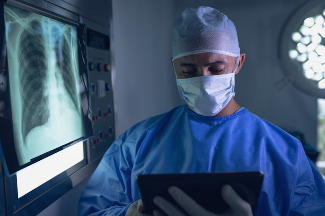 Male surgeon examining x-ray report on digital tablet in operating room - Download Free Stock Photos Pikwizard.com