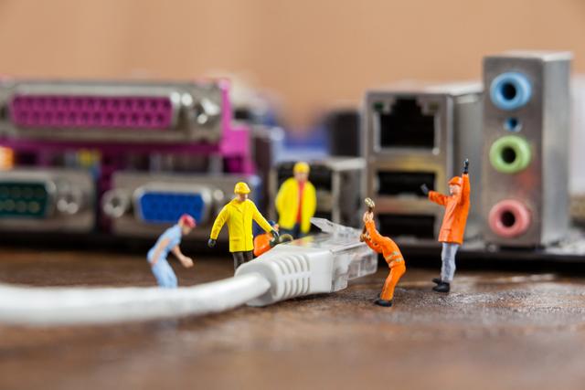 Miniature engineer and worker plug-in lan cable to computer - Download Free Stock Photos Pikwizard.com