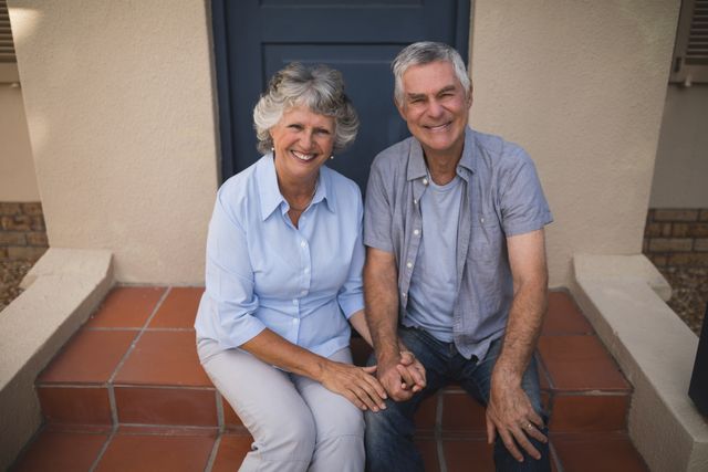 Portrait of smiling senior couple sitting together against house - Download Free Stock Photos Pikwizard.com