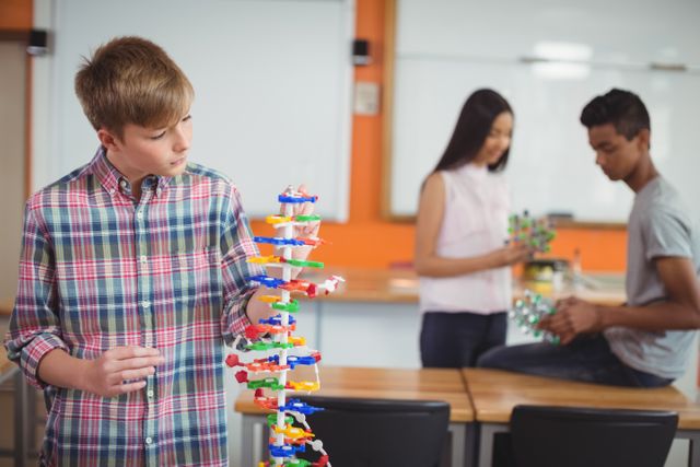 Schoolboy examining molecule model in laboratory at school