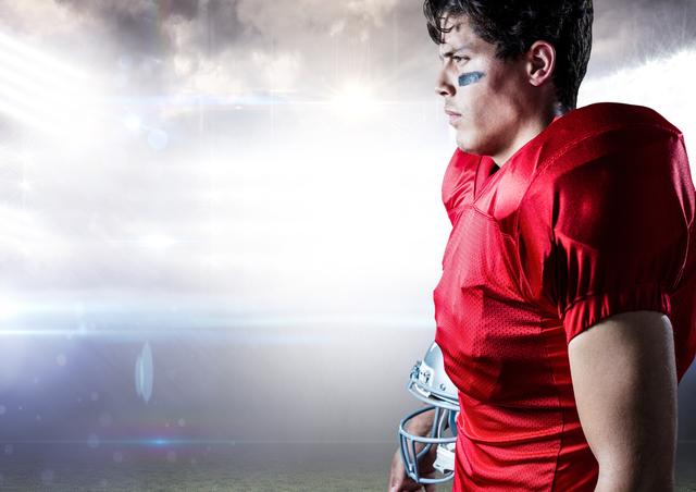 American football player holding helmet against illuminated background - Download Free Stock Photos Pikwizard.com