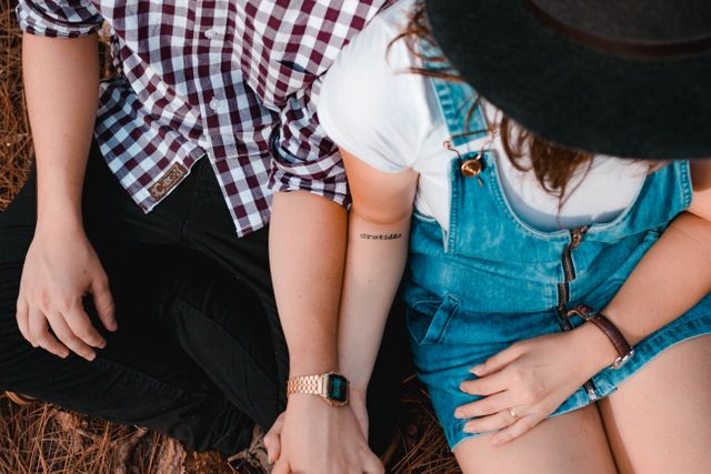 Mid section of couple holding hands sitting on hay stack. Love and relationship concept