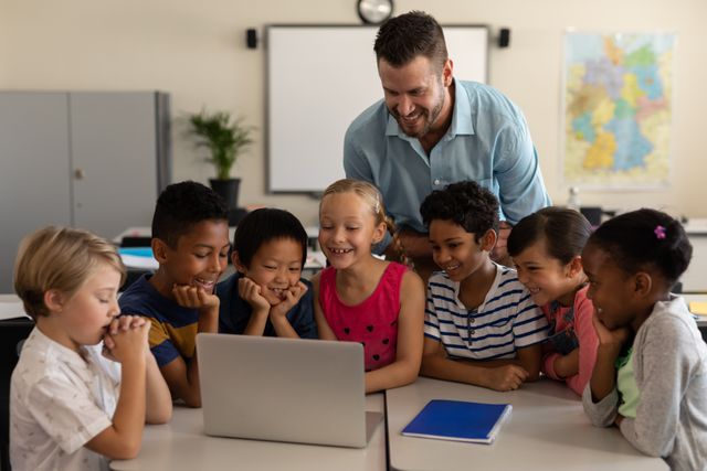 Male teacher teaching kids on laptop in classroom - Download Free Stock Photos Pikwizard.com