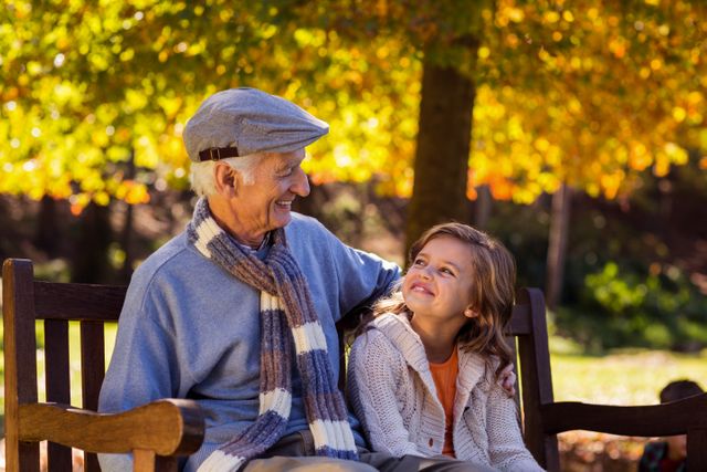 Grandfather sitting with granddaughter at park - Download Free Stock Photos Pikwizard.com