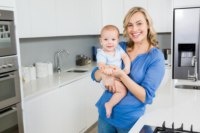 Portrait of mother holding her baby boy in kitchen - Download Free Stock Photos Pikwizard.com