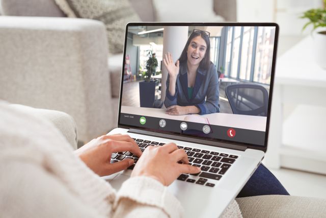 Caucasian businesswoman waving hand to caucasian female colleague during video call. unaltered, work from home, business, wireless technology, working, teamwork and office concept.