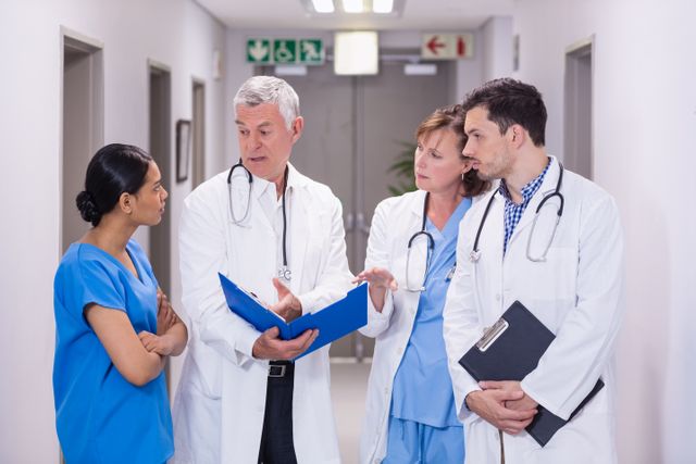 Nurse and doctors discussing over clipboard - Download Free Stock Photos Pikwizard.com