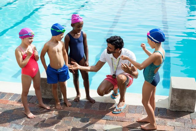 Male trainer assisting children at poolside - Download Free Stock Photos Pikwizard.com