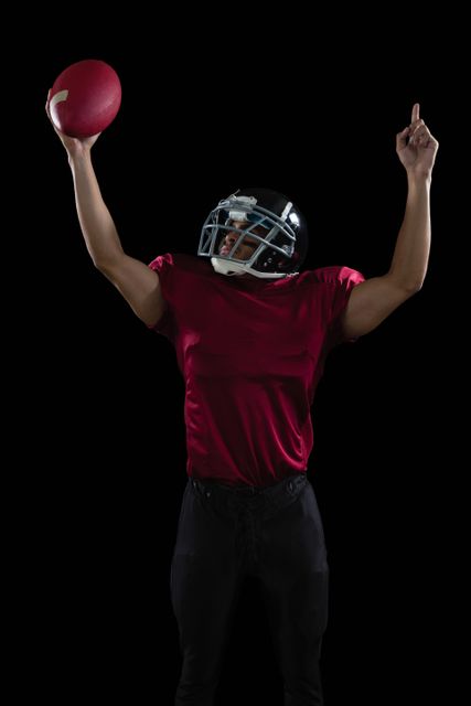American football player raising hands holding a ball high in one hand - Download Free Stock Photos Pikwizard.com