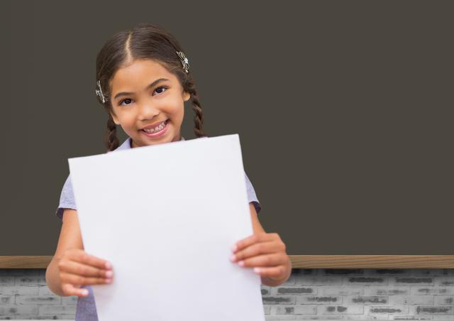 School girl holding blank paper against blackboard in background - Download Free Stock Photos Pikwizard.com