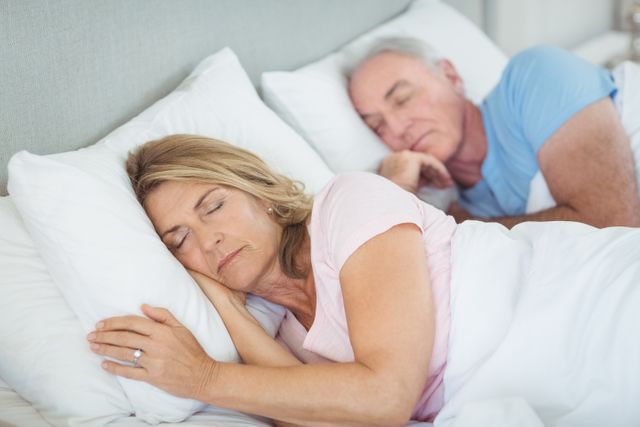 Senior couple sleeping together on bed in bedroom