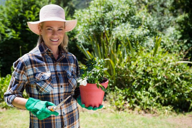 Portrait of happy woman holding sapling and trowel in garden - Download Free Stock Photos Pikwizard.com