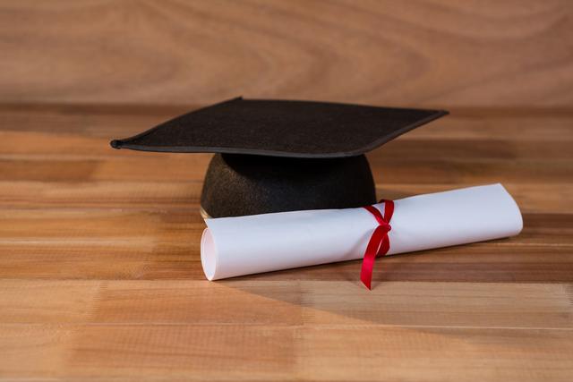 Close-up of graduation certificate with mortar board on a table - Download Free Stock Photos Pikwizard.com