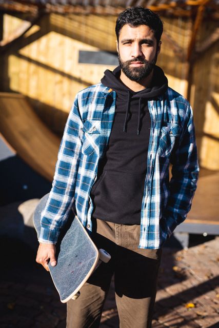 Portrait of biracial man in skateboard shop holding skateboard - Download Free Stock Photos Pikwizard.com