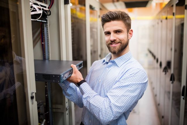 Portrait of technician removing server from rack mounted server in server room