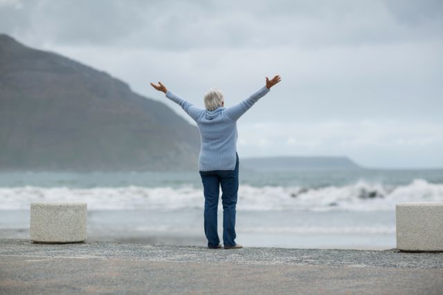 Senior woman standing with arms outstretched on the beach - Download Free Stock Photos Pikwizard.com
