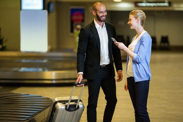 Smiling couple interacting with each other in waiting area at airport terminal 