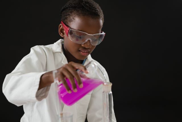 Attentive schoolgirl doing a chemical experiment against black background
