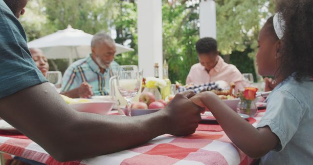Happy african american family sitting at table in garden, praying together - Download Free Stock Photos Pikwizard.com