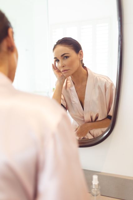 Woman looking at her face in the mirror at bathroom - Download Free Stock Photos Pikwizard.com