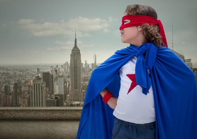 Superhero kid in blue cape and red eye mask standing with cityscape in background - Download Free Stock Photos Pikwizard.com