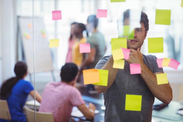 Business executive reading sticky notes in office