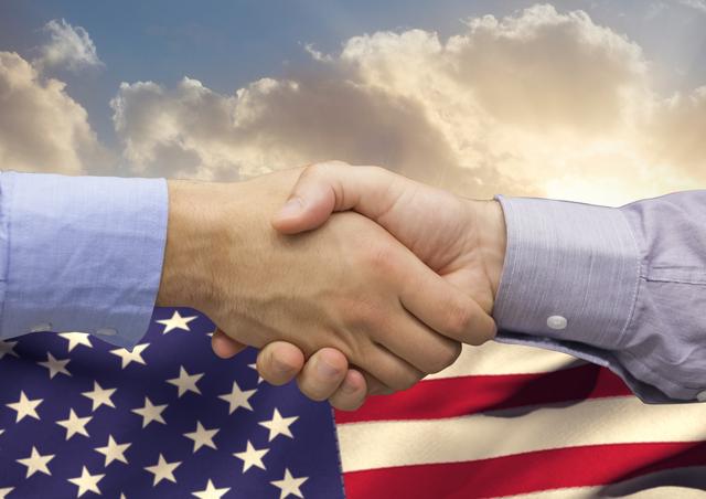 Digital composition of business executives shaking hands against american flag in background