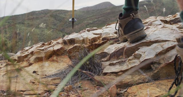 Feet of caucasian male survivalist walking on rocky mountain, using walking poles. exploration, travel and adventure, survivalist in nature.